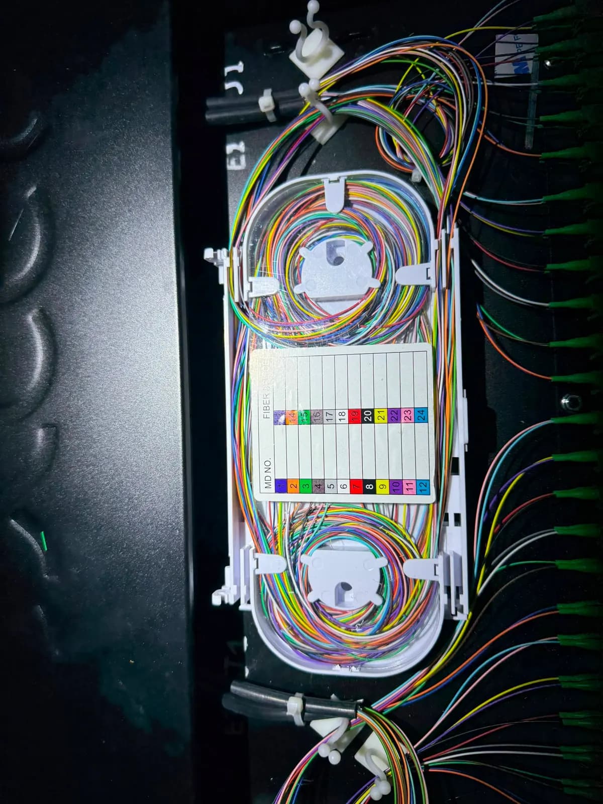 Cassette d'épissure dans un tiroir noir, fibres repérées par couleur